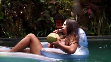 Güzel bir kadın, gün batımında havuz kenarında lüks bir sahil otelinin kaplıcasında dinleniyor. Mükemmel bir plaj tatili ve seyahat görüntülerinin keyfini çıkarıyor.