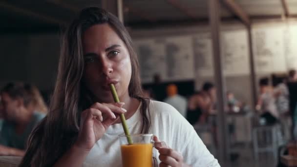 Joven atractiva mujer bebiendo zumo de mango tropical fresco batido usando cero residuos ecológicos orgánico reutilizable Strawin restaurante vegano . — Vídeo de stock