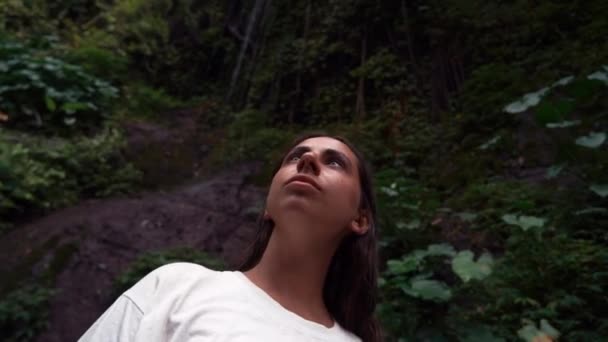 Άποψη χαμηλή γωνία Μια νεαρή σοβαρή γυναίκα κοιτάζοντας ζούγκλα με λυπημένο πρόσωπο. Κοντινό πλάνο της όμορφης γυναίκας κοιτάζοντας γύρω στο σκοτεινό δάσος εξωτερική — Αρχείο Βίντεο