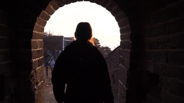 Une femme heureuse marche à la Grande Muraille de Chine, descend de la tour de guet de la section Badaling au coucher du soleil en hiver. Concept de voyage — Video