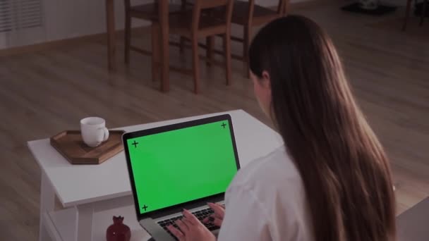 Hemma isolerad. Kvinna hemma Sitter på en soffa Fungerar på en bärbar dator med grön Mock-up skärm. Coronavirus Covid-19 sätter distansutbildning eller arbetskoncept i karantän. Flicka med hjälp av dator, bläddrar — Stockvideo