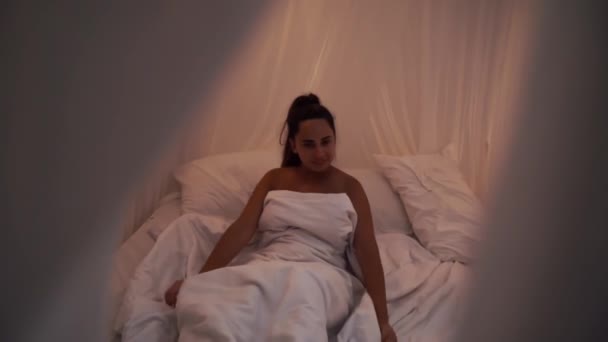 Mooie Brunette Langzaam wakker in de ochtend, strekt zich uit en staat op uit het bed met luifel. Gelukkig jong meisje groet nieuwe dag — Stockvideo