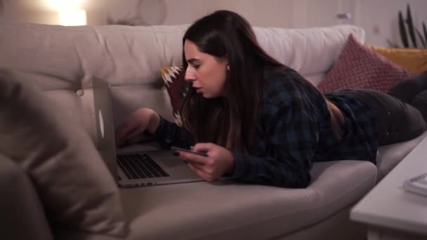 一个人在家漂亮的女人躺在沙发上，用信用卡在家里网上购物。Coronavirus Covid-19检疫概念 — 图库视频影像