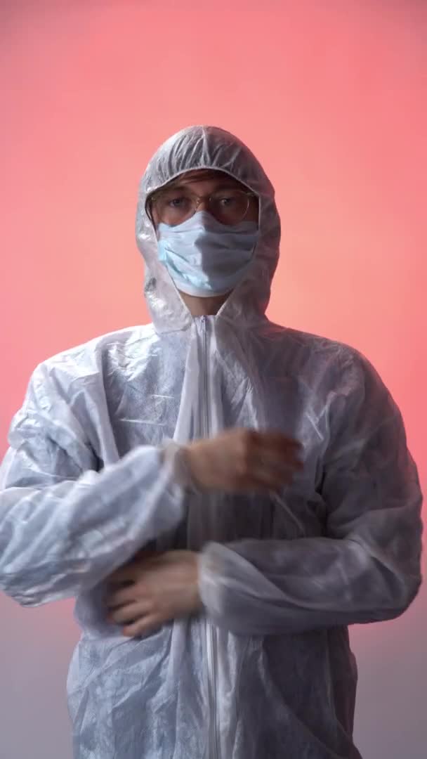 Une personne en combinaison de protection, enlève le masque médical et respire de l'air frais sans virus. Le concept de santé et de liberté sans coronavirus. Vidéo verticale — Video