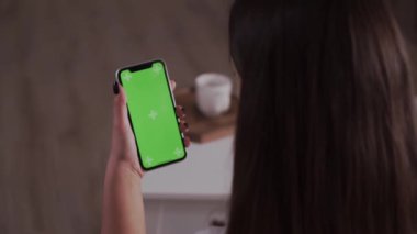 Ev soyutlanmış. Krom anahtar taşıyan esmer, yeşil ekran akıllı telefonun arkadaşıyla sohbet edişinin arka görüntüsü. Coronavirus Covid-19 Karantina Uzaktan eğitim veya çalışma konsepti