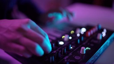 Ev kayıt atölyesinde DJ 'in müzik çalarkenki yakın çekimi. Öğrenci yaratıcı atmosfer müziği yazmayı öğreniyor. Çevrimiçi eğitim. Ses çıkarıcı. Renkli Neon ışığı