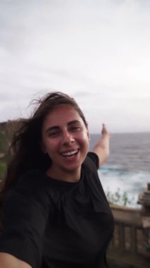 Tatilde, deniz manzaralı dağlarda bulunan kız, evden arkadaşları ve aileleriyle fotoğraf, selfie ve video görüşmeleri yapmak için telefonu kullanıyor. Kavram: Kutlama, teknoloji, aşk