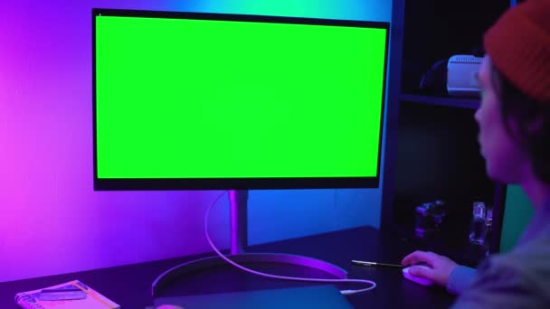 Людина працює на своєму персональному комп'ютері з великим зеленим екраном Mock Up Display. Він працює в будинку в неоновому світлі. Домашній самоізоляційний карантин коронавірус ncov-19 — стокове відео