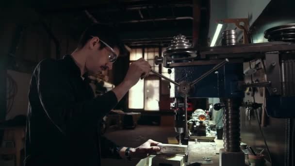 Ο εργάτης δουλεύει στο τρυπάνι του μηχανήματος στο εργοστάσιο. Ξυλουργικές. Ξυλουργός. Ένας άντρας δουλεύει πίσω από μια μηχανή γεώτρησης. Ηλεκτρική μηχανή γεώτρησης. Μύλος σε δέντρο. — Αρχείο Βίντεο