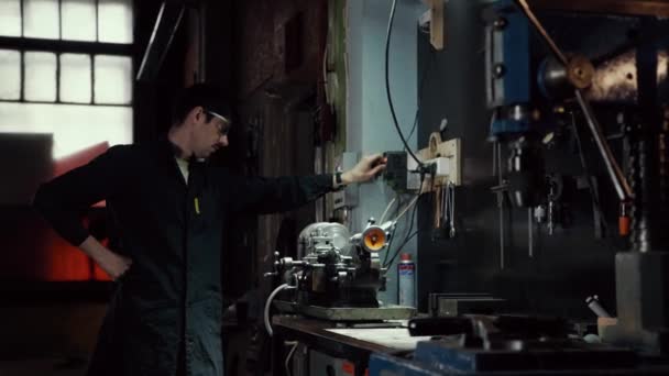 Εργάτης με γυαλιά εργάζεται σε μια μηχανή άλεσης στο εργοστάσιο. Η έννοια της παραγωγής και των κατασκευών — Αρχείο Βίντεο