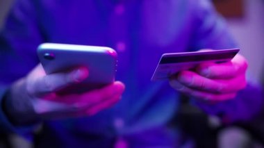Akşamları evde karantina altında neon ışığı olan bir odada internetten mal ve ürün alan bir adam. Çevrimiçi bankacılık ve akıllı telefon. Akıllı telefon ya da dijital cihaz kullanarak kolay para kazanılır. Ev