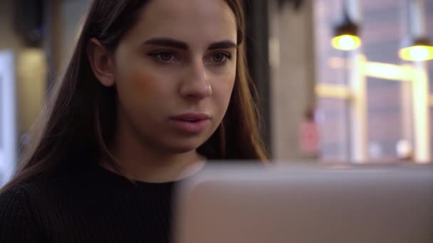 Young Beautiful Brunette werkt op een Laptop Computer in Cool Creative Agency in een Loft Office. Ze heeft een afhaalkoffie en een notitieboekje op haar tafel.. — Stockvideo