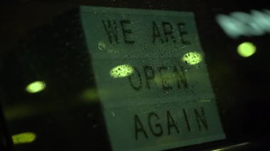 Işıkkutusuyla birlikte, akşam yağmur yağarken, kafenin cam kapısının arkasında tekrar açığız. Karantinadan sonra tekrar açıldı. Küçük işletme sahibinin videosu. Lütfen maske takın ve...