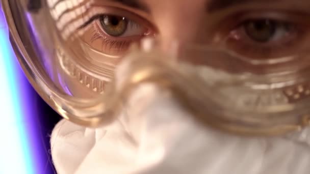 Dokter, viroloog, wetenschapper vrouw met bril en een medisch masker aan het werk. artsen ogen met een beschermend masker. Macro sluit af. Concept coronavirus COVID-19 — Stockvideo