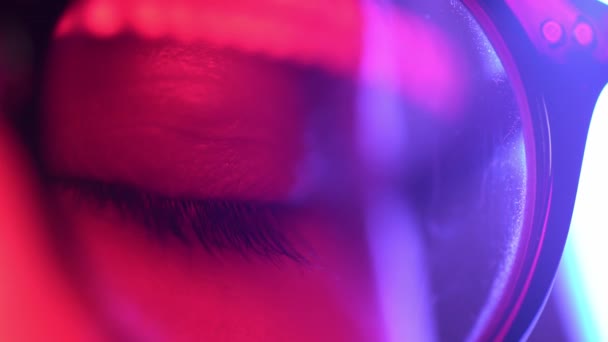 Close up Makro Frau blaues Auge in einer Brille öffnen schöne Iris natürlichen Menschen in Neonlicht. Schönheit und gesundes Sehvermögen — Stockvideo