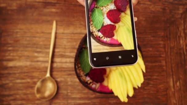 Vrouwelijke handen fotograferen smakelijk eten per smartphone in het restaurant. Traditioneel ontbijt in Bali Indonesië — Stockvideo