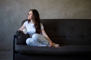 Kanepe ve çay içme kadın oturur