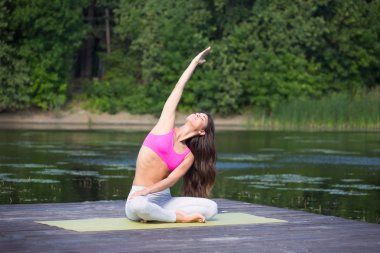 Genç kız uygulamaları yoga göle zevk gizlilik ve konsantrasyon, güneş ışığı kavramı kıyısında