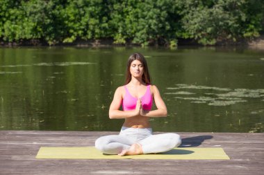 Genç kız uygulamaları yoga göle zevk gizlilik ve konsantrasyon, güneş ışığı kavramı kıyısında