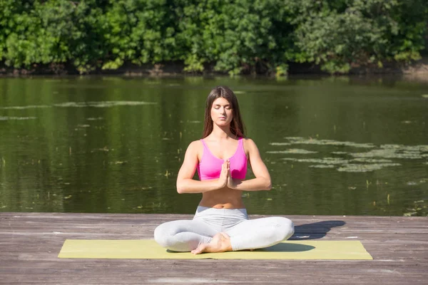Genç kız uygulamaları yoga göle zevk gizlilik ve konsantrasyon, güneş ışığı kavramı kıyısında
