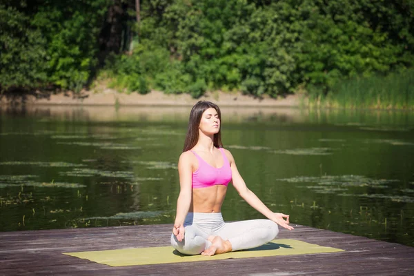 Genç kız uygulamaları yoga göle zevk gizlilik ve konsantrasyon, güneş ışığı kavramı kıyısında