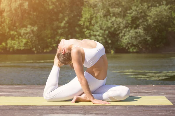 Genç kız uygulamaları yoga göle zevk gizlilik ve konsantrasyon, güneş ışığı kavramı kıyısında
