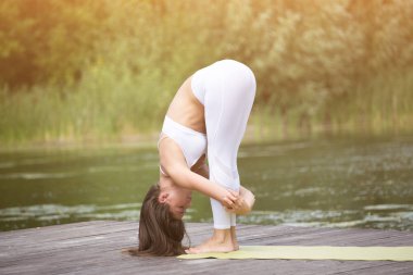 Genç kız uygulamaları yoga göle zevk gizlilik ve konsantrasyon, güneş ışığı kavramı kıyısında