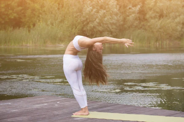 Młoda dziewczyna praktyk jogi na brzegu jeziora, koncepcja korzystających z prywatności i koncentracji, światło słoneczne — Zdjęcie stockowe