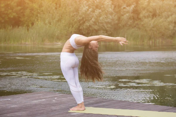 Genç kız uygulamaları yoga göle zevk gizlilik ve konsantrasyon, güneş ışığı kavramı kıyısında
