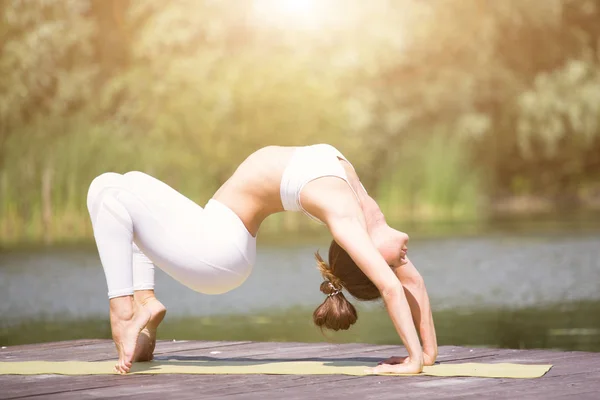 Genç kız uygulamaları yoga göle zevk gizlilik ve konsantrasyon, güneş ışığı kavramı kıyısında