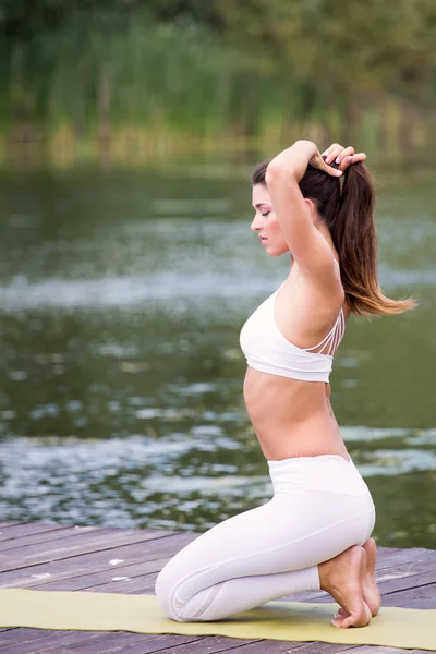 Genç kız uygulamaları yoga göle zevk gizlilik ve konsantrasyon, güneş ışığı kavramı kıyısında