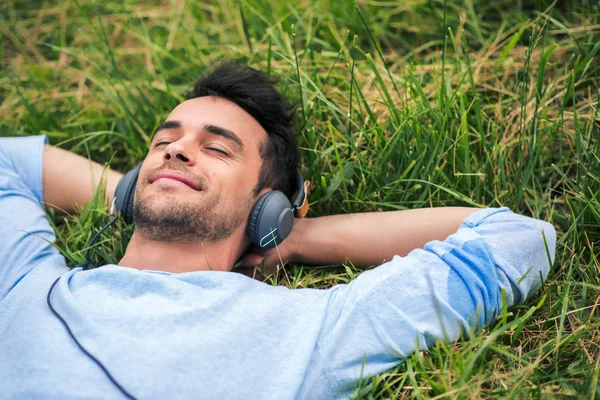 Портрет молодого усміхненого чоловіка, який насолоджується і мріє з навушниками, слухати музику — стокове фото