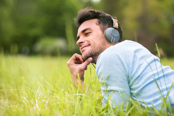 Sevimli genç yeşil çimen dinle müzik yalan adam ve onun arkasından bak