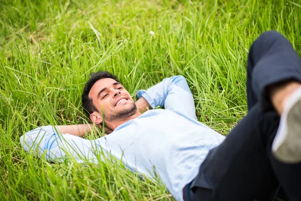 Bonito homem na grama verde com seu olhar dispositivo de volta . — Fotografia de Stock