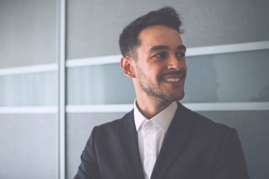 Portre gülümseyen ve mutlu işadamı takım elbise üzerinde office arka plan üzerinde bir tarafa bak.