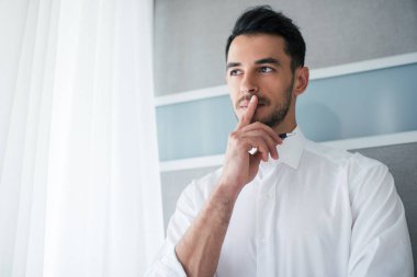 Bir tarafta seyir ağzına bir parmak ile Beyaz gömlekli yakışıklı işadamı düşünüyorum. İş. Alt görünümü.