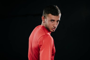 Koyu arka plan üzerinde duran, onun hayatında sorunları üzerinde düşünme, beline üzerinde el ele tutuşarak, uzağa arıyorsunuz kırmızı spor giyim kaslı sporcu adam görünümünü profil. Yaşam tarzı, spor, motivasyon.