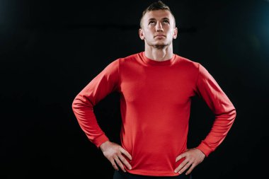 Ararken yakışıklı genç Beyaz atlet, koyu arka plan ayakta ve beline üzerinde el ele tutuşarak, sert çalışmadan sonra rahatlatıcı portresi. Yaşam tarzı, spor, motivasyon.