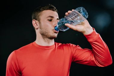 Çekici genç Avrupa sporcu içme suyu kırmızı spor giyim, çalıştırdıktan sonra rahatlatıcı ya da egzersiz şişe, bardak kapatın. Spor motivasyon. Yaşam tarzı.
