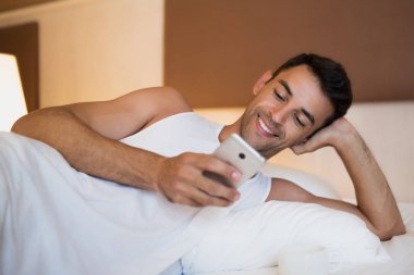 Bir cep telefonu kullanarak ve içinde mesajlaşma genç gülümseyen yakışıklı adam