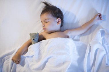 Beyaz yatakta uyuyan güzel bebek, yukarıdan görüntülemek