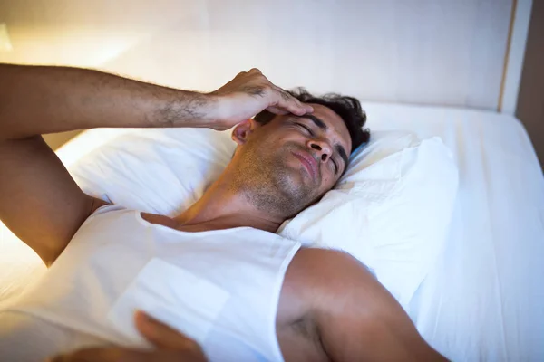 Un hombre guapo con dolor de cabeza acostado en la cama blanca. Dormitorio b — Foto de Stock