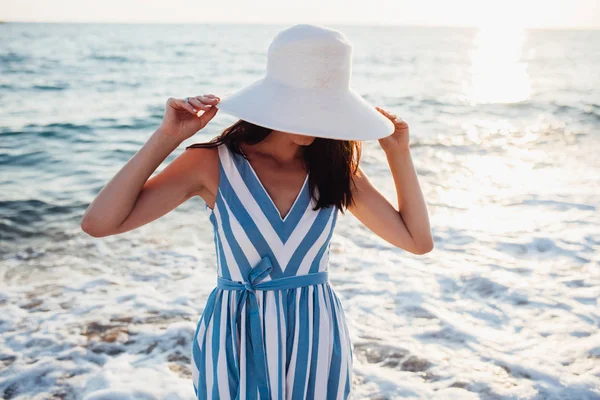 Mulher bonita atraente com chapéu branco na cabeça no por do sol do mar — Fotografia de Stock