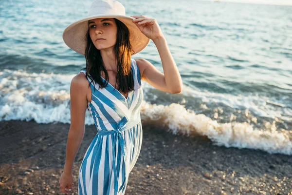 Morena bela mulher com chapéu branco, andando ao longo da praia e — Fotografia de Stock