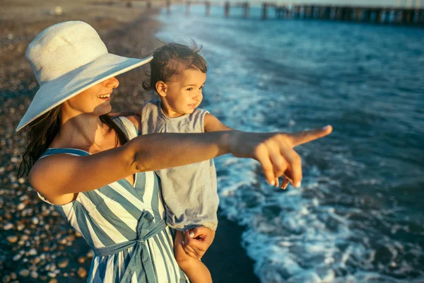 Porträtt av ung mamma leende med dotter med vit hatt på t — Stockfoto