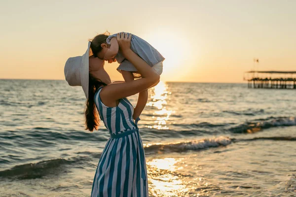 바다 석양과 해변에서 아름 다운 젊은 어머니 키스 딸 — 스톡 사진