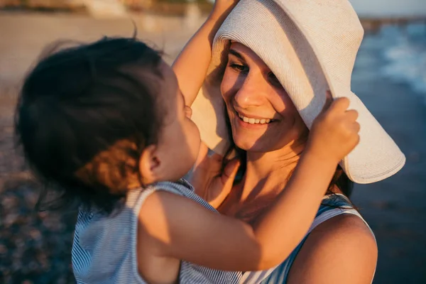 Молодая мать играла с дочкой в белой шляпе — стоковое фото