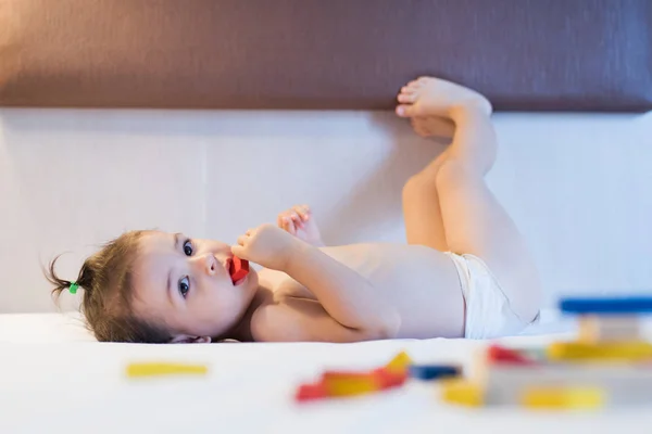 Χαριτωμένο όμορφο μικρό παιδί κορίτσι ξαπλωμένο στο κρεβάτι σε ένα playi χάος παιχνίδι — Φωτογραφία Αρχείου