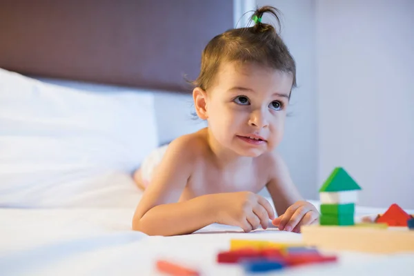 Портрет маленькой красивой девочки, лежащей на кровати в игрушечной коробке — стоковое фото