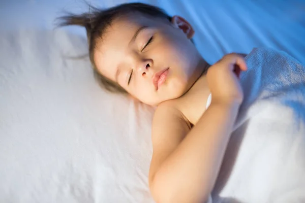 Πορτραίτο του αξιολάτρευτο κοριτσάκι που κοιμάται στο λευκό κρεβάτι τη νύχτα. L — Φωτογραφία Αρχείου